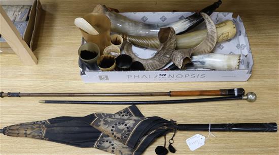 A collection of powder horns, horn beakers and a silver vesta case, two sticks and a parasol